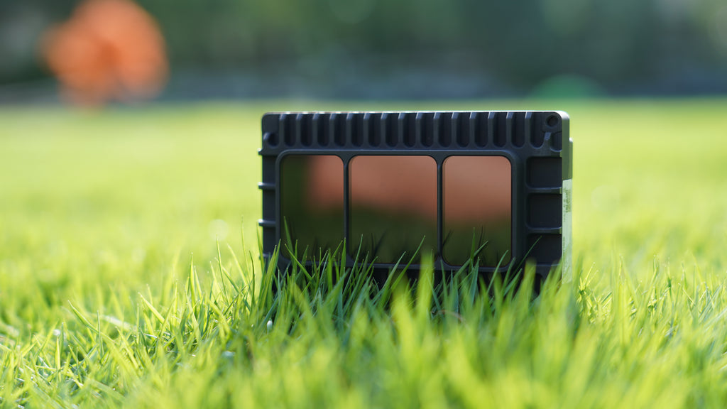 E1R solid-state digital LiDAR with three black sensing windows resting in grass